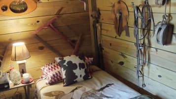 Une pièce rustique en bois, avec un lit, une lampe et des accessoires de chasse accrochés au mur.