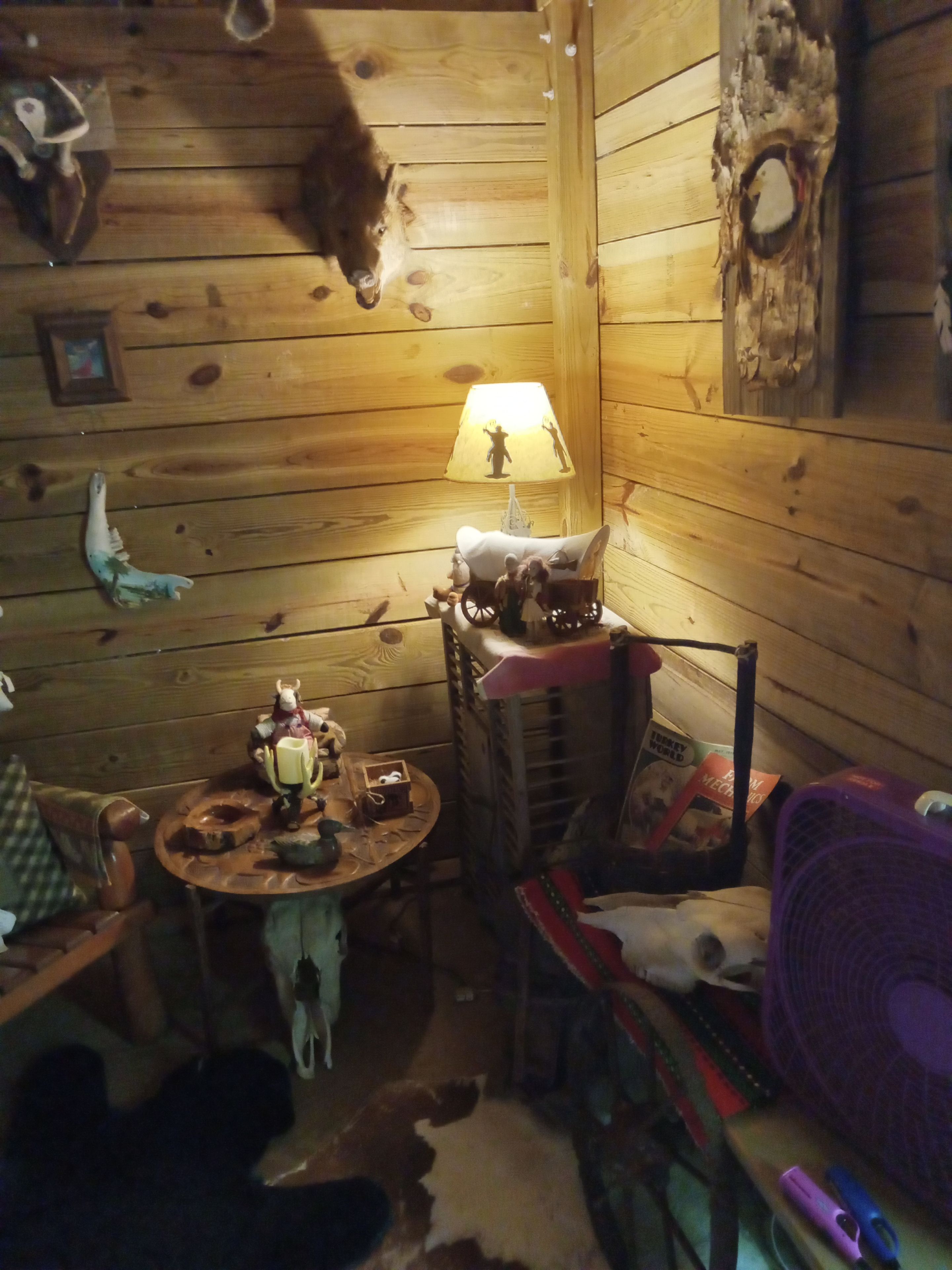 L’intérieur d’un chalet accueillant, avec des murs en bois, une petite table sur laquelle sont disposés divers objets, une lampe et une chaise.