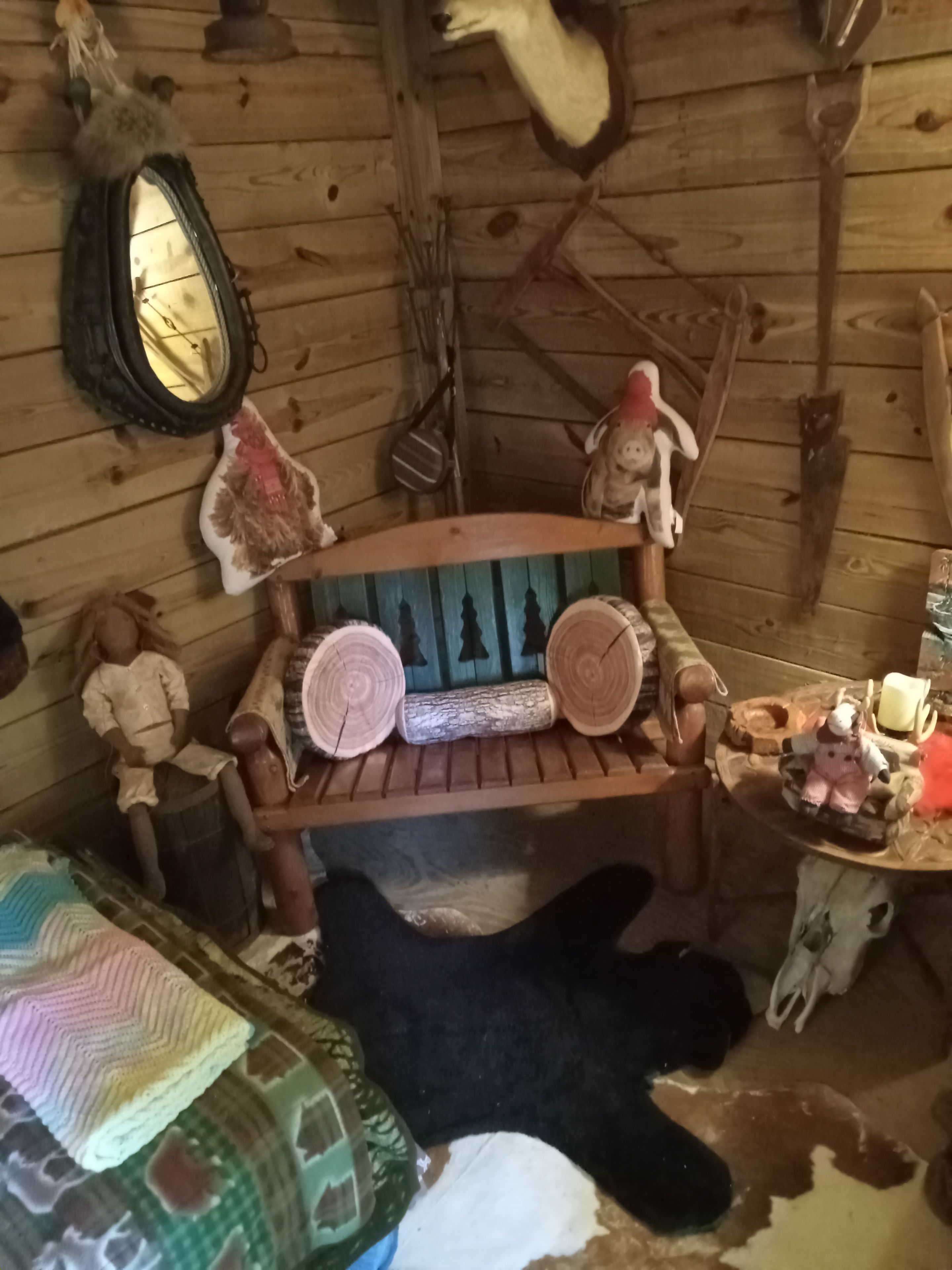 L’intérieur d’un chalet rustique, avec un banc en bois, une petite table ornée de bougies et un miroir fixé au mur.