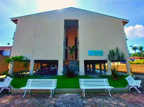 A building with a flat roof, a central entrance, and a sign above it. There are two covered parking areas on either side of the entrance. - Ubatuba Best Location (Ubatuba)