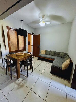 A compact living space with a dining area, a sofa, and a ceiling fan. - Ubatuba Best Location (Ubatuba)