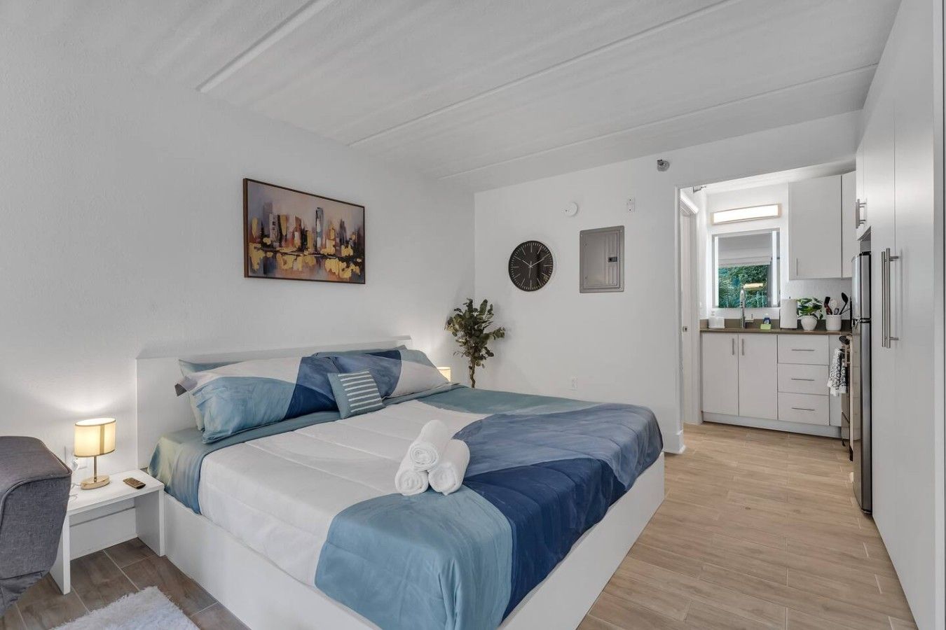 A bedroom with a bed, bedside table, lamp, and a painting on the wall.
