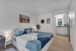 A bedroom with a bed, bedside table, lamp, and a painting on the wall. - 7 Min to Disney, Cozy Suite + Free Parking | Orl (Kissimmee)