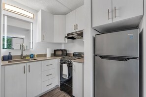 A modern kitchen with stainless steel appliances, including a refrigerator, oven, and microwave. - Orlando Studio | Disney Nearby + Resort Pool | Orl (Kissimmee)
