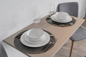 A dining table set with white plates, silverware, and a glass of water. - Disney Magic 7 Min Away + Free Parking and Pool (Kissimmee)