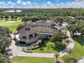A large, multi-story residential building with a tiled roof, surrounded by well-maintained lawns and trees. - Disney Magic 7 Min Away + Free Parking and Pool (Kissimmee)