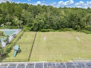A fenced sports field with a goalpost and a slide, surrounded by trees. - Disney Magic 7 Min Away + Free Parking and Pool (Kissimmee)
