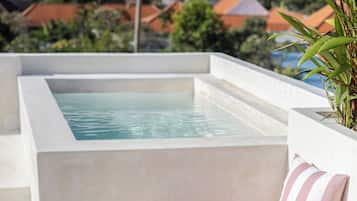Un espace piscine aménagé sur le toit, avec un coin salon et une table où l’on peut prendre une boisson.