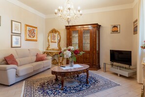 Un salon comprenant un canapé, un téléviseur, un lustre et un meuble.