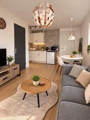 Ein modernes Wohnzimmer mit einem grauen Sofa, einem Holztisch und einem runden Teppich.