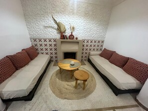 A room with two sofas, a small round table, and a fireplace. - Vrbo Property (Marrakech)