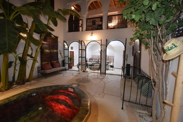 Un área de piscina interior con un jacuzzi, asientos y una escalera que conduce a un nivel superior.