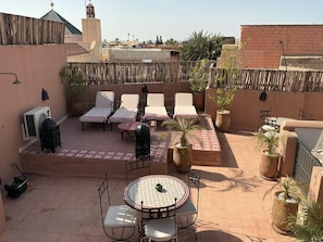 Terraza en la azotea con sillones, una mesa y plantas en macetas.