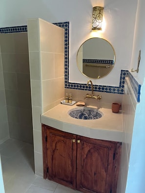 Un baño con lavamanos, espejo y una lámpara en la pared.