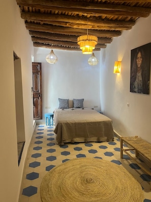 Un dormitorio con una cama, dos lámparas de pared, una puerta de madera y un suelo estampado.