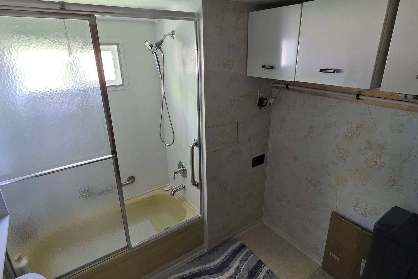 A bathroom with a glass-enclosed shower, a white sink, and a cabinet above the sink.