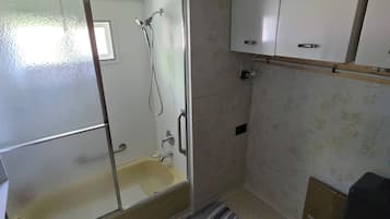 A bathroom with a glass-enclosed shower, a white sink, and a cabinet above the sink.