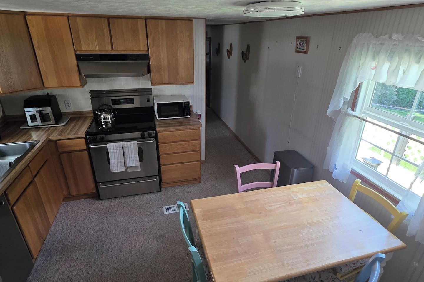 A compact kitchen with wooden cabinets, a microwave, an oven, and a small dining table with chairs.