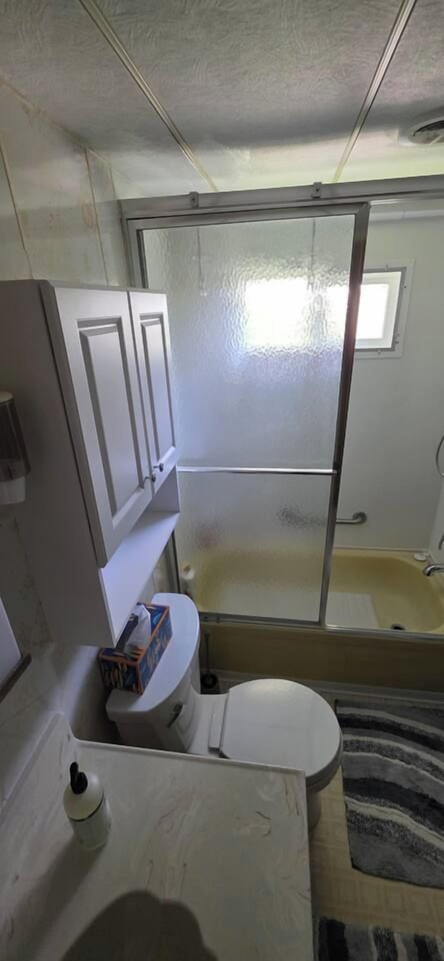 A compact bathroom with a toilet, a small window, and a bathtub.