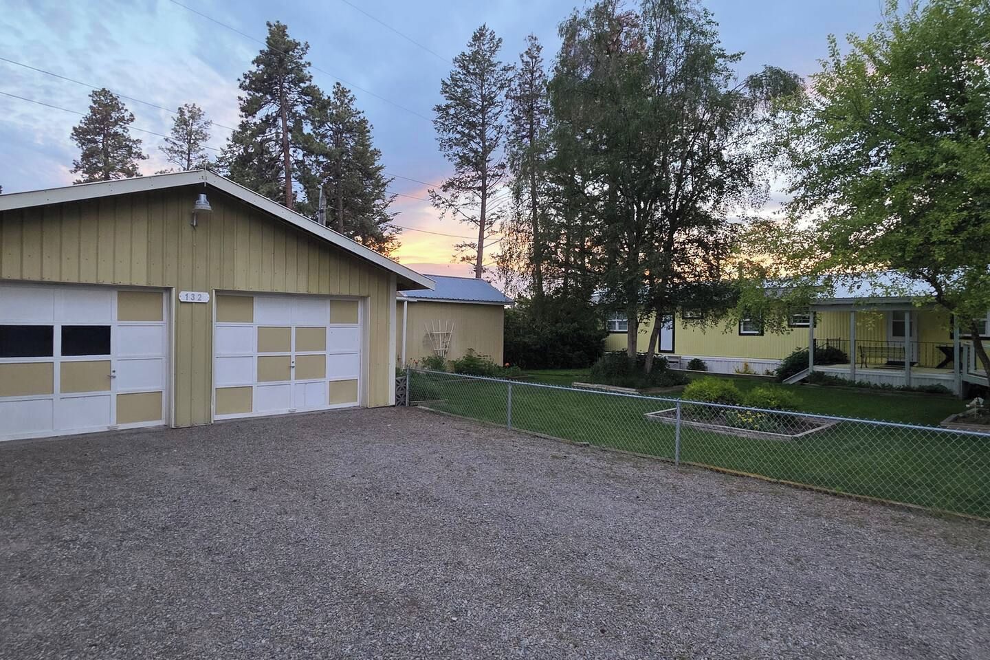 A building with a garage and a fenced yard.