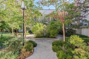 Un sentier qui traverse un jardin aménagé, avec des bancs et une clôture.