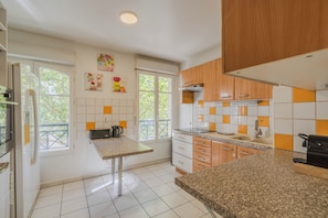Une cuisine moderne avec des carreaux blancs et orange, un comptoir en granit et des armoires en bois.