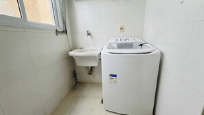 Un bany petit i net amb un lavabo i una rentadora compacta.