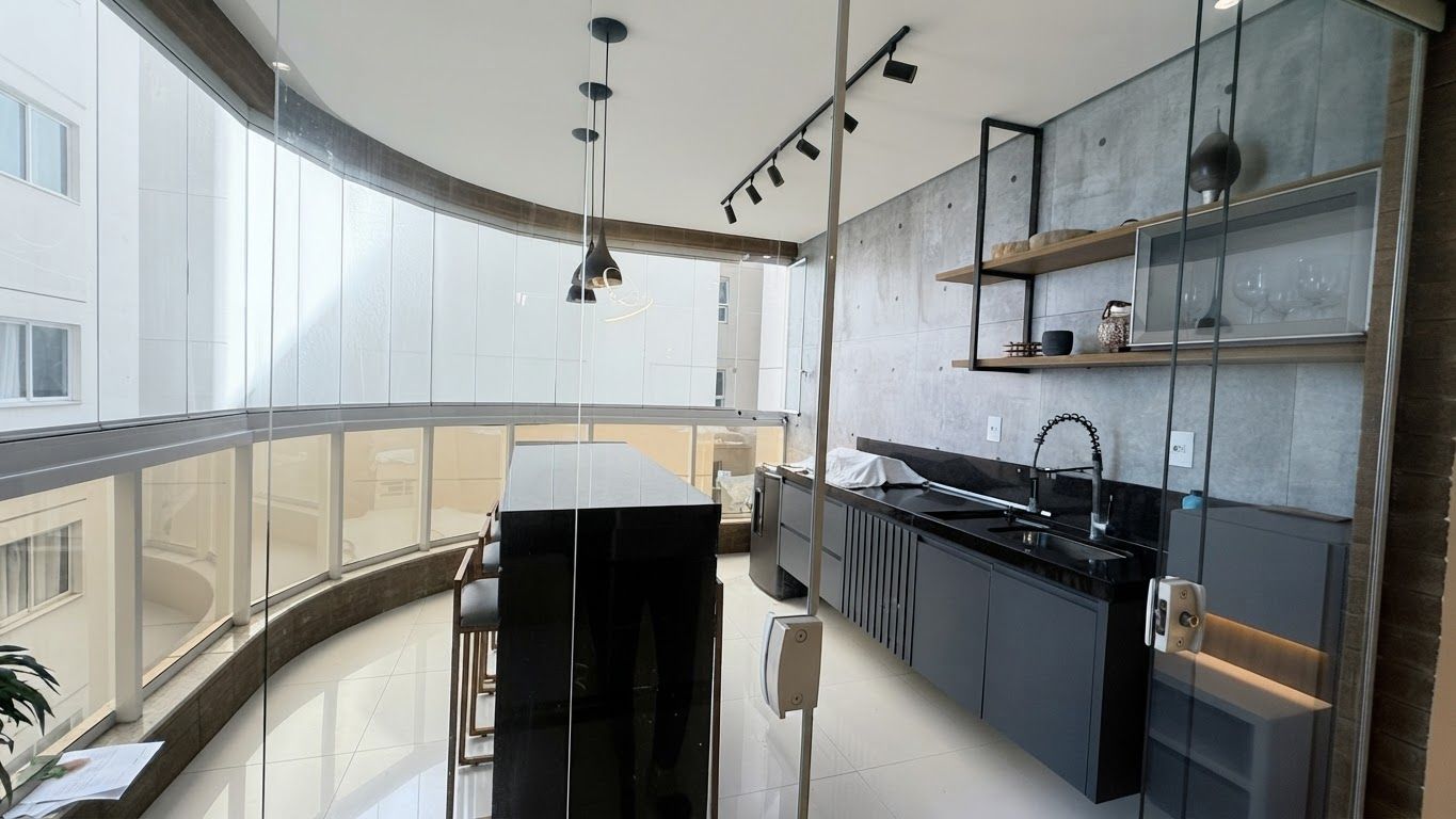 A modern kitchen with a curved countertop, black cabinetry, and a glass backsplash.