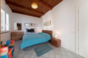 A bedroom with a bed, bedside table, lamp, TV, and artwork on the wall. - Holiday Home 'La Casa Sul Porto Ischia' with Sea View, Wi-Fi and Air Conditioning (Ischia)