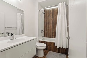 Un baño moderno con lavamanos, inodoro y bañera blancos.