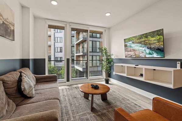 Una sala de estar moderna con sofá, mesa de centro y mueble para la televisión.