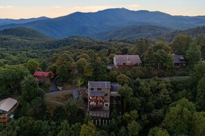 Ein Wohngebiet mit mehreren Häusern, umgeben von dichtem Wald und Bergen im Hintergrund.