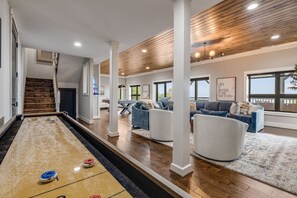 A spacious living area with a shuffleboard table, a staircase, and a large window with a view. - Mtn Views, Game Room, Fire Table, Porches (Blowing Rock)