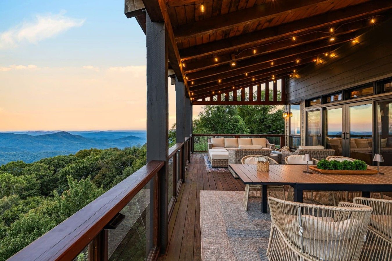 A deck with outdoor furniture, a table, and a view of the mountains.