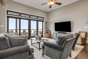 A spacious living room with a large TV, comfortable seating, and a balcony with outdoor furniture. - Mtn Views, Game Room, Fire Table, Porches (Blowing Rock)