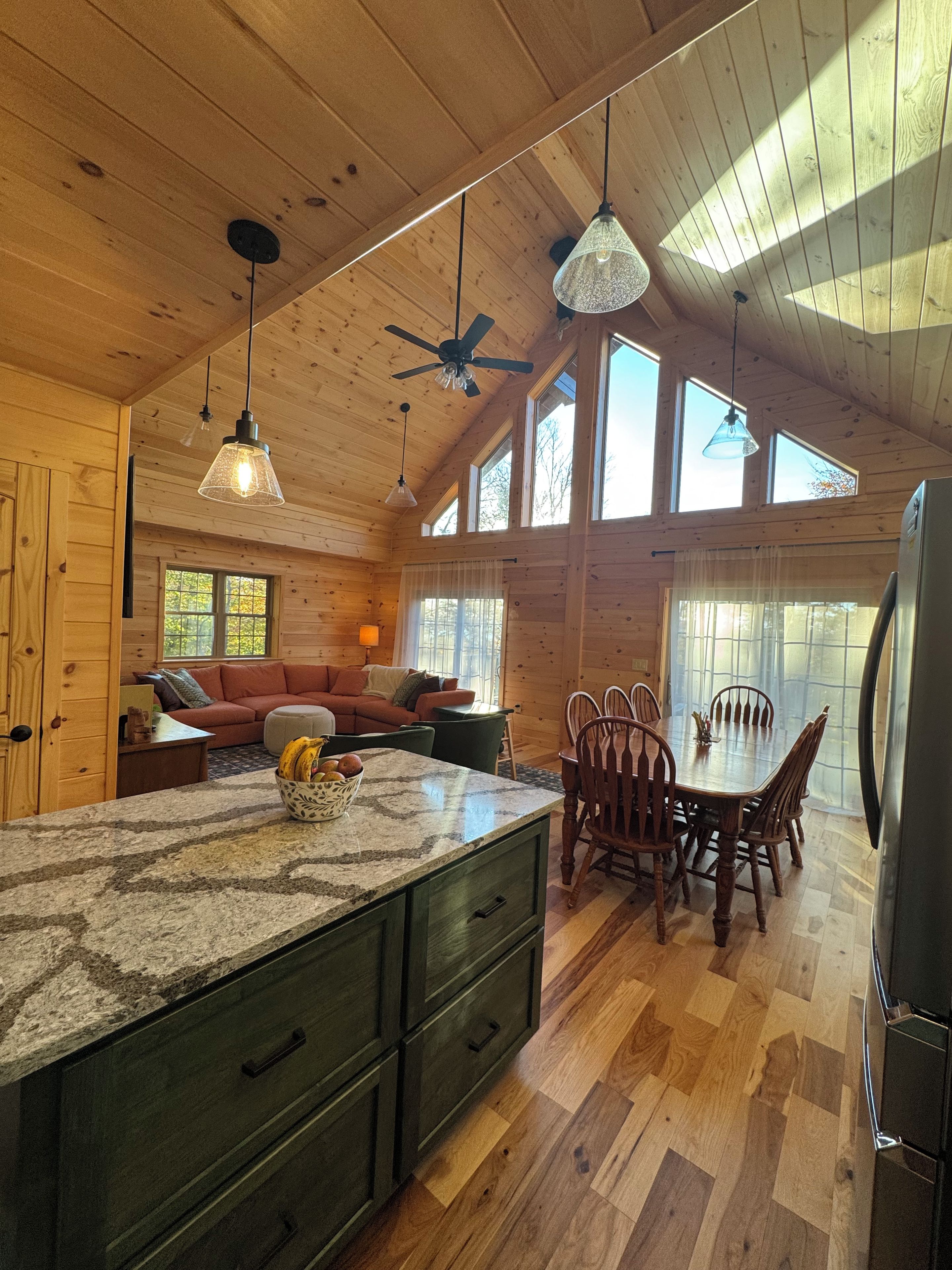 Interior de una cabaña de madera con cocina, comedor y sala de estar.