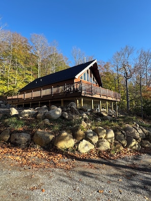 A cabin with a wooden deck and large rocks in front. - The Friendly Fern - Welcoming Old Friends and New (Old Forge)