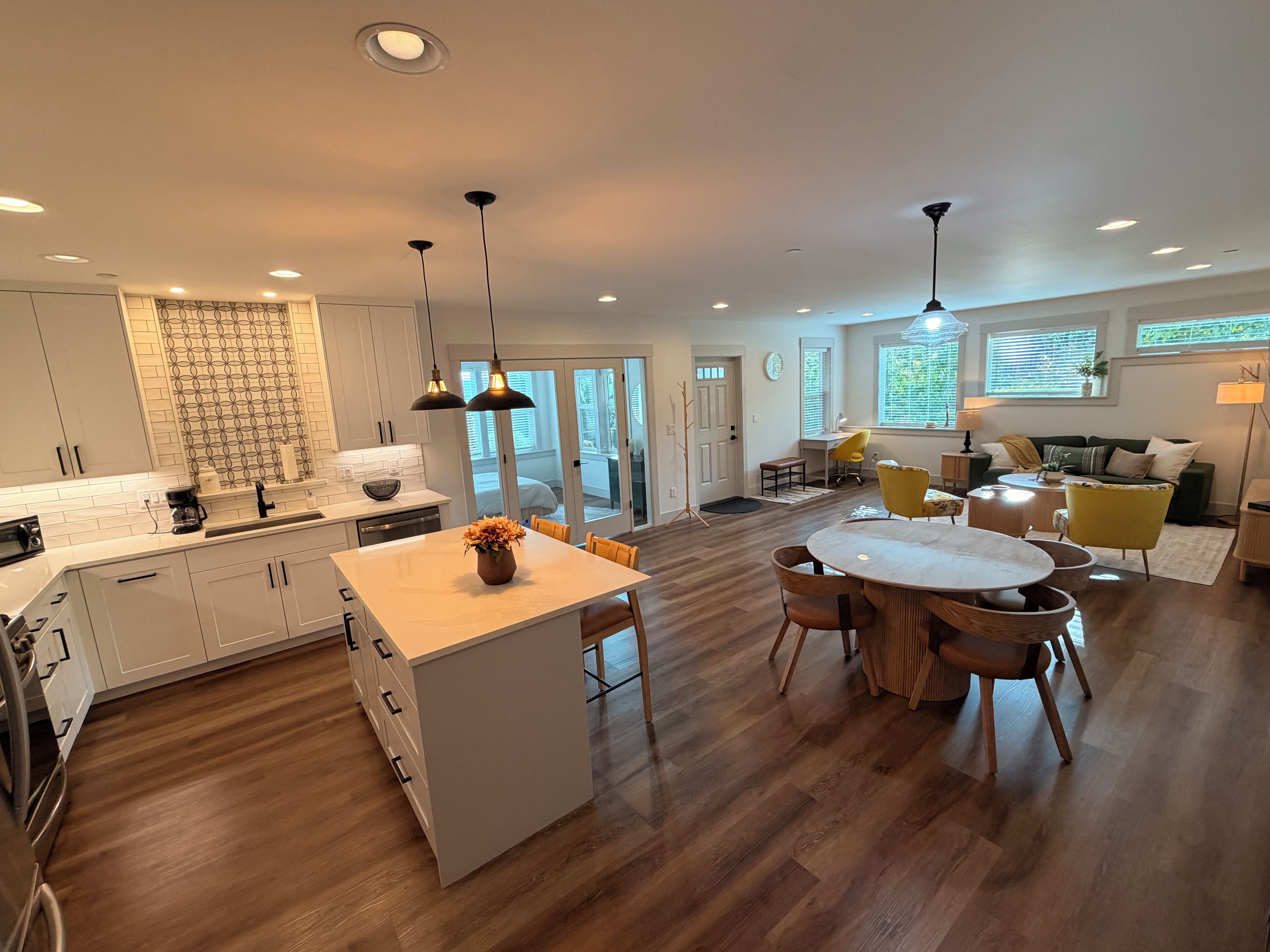 A modern kitchen with white cabinets, a central island, and pendant lighting.