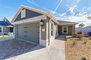 A residential house with a garage, a driveway, and a landscaped garden. - The Big Cat 3BR | Lanai | Near Brownwood (The Villages)