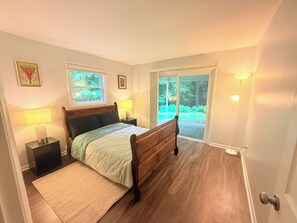 Ett sovrum med en säng, två sänglampor, ett fönster och en dörr som leder ut till en balkong.