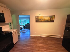 Ett kök med en spis, skåp och en matplats med en soffa och ett bord.