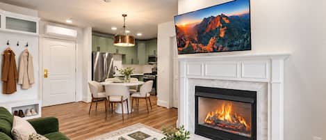 Una sala de estar moderna con chimenea, un comedor y una cocina al fondo.