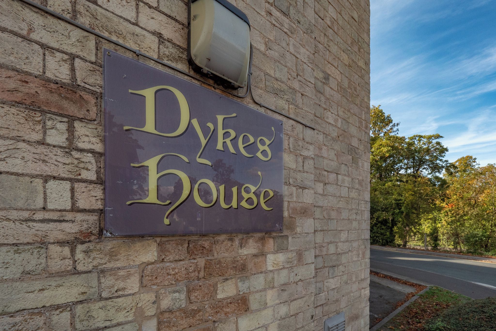En skylt med texten ”Dykes House” på en byggnad med tegelväggar.