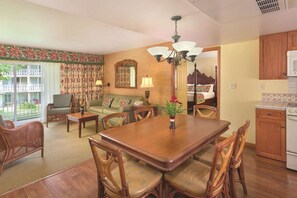 A dining area with a wooden table and chairs, a sofa, a lamp, and a view of the outside. - 1 BR Garden Suite at Kapa'a Oceanfront Resort (Kapaʻa)