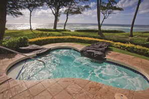 A pool with a view of the ocean, surrounded by a landscaped garden with trees and a well-maintained lawn. - 1 BR Garden Suite at Kapa'a Oceanfront Resort (Kapaʻa)