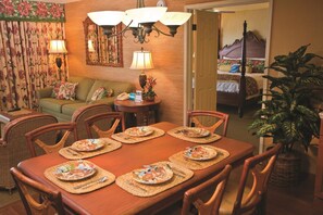 Un coin repas avec une table en bois dressée pour quatre personnes, entourée de chaises en osier.