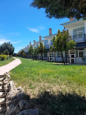 A row of two-story buildings with balconies, a paved path, and a grassy area. - Aydın Palace Termal (Ihsaniye)