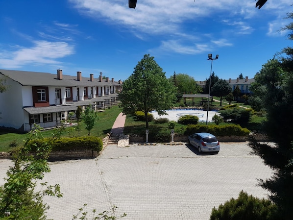 A residential area with a paved driveway, a parked car, and a row of houses with a clear sky above. - Aydın Palace Termal (Ihsaniye)