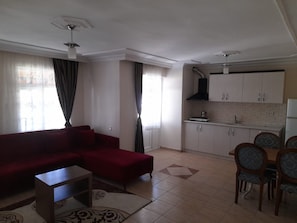 Una sala de estar con un sofá rojo, una mesita y un comedor con sillas.