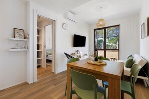 A modern dining area with a wooden table, green chairs, and a view of the outdoors through large windows. - Apartment 'Salsedine's House' with Private Garden, Wi-Fi and Air Conditioning (Arboriamar)
